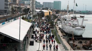 vista aérea geral do parque valongo, com o mar à direita e a roda gigante ao fundo. Pessoas circulam pelo local. #paratodosverem 