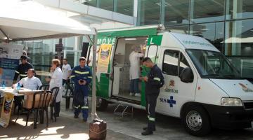 van odontológica está parada em frente a terminal. diante dela há uma tenda com pessoas usando avental branco. Trabalhadores portuários estão uniformizados. #paratodosverem