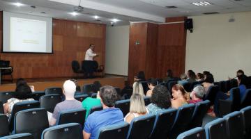 homem está em palco dando palestra em auditório. #paratodosverem 