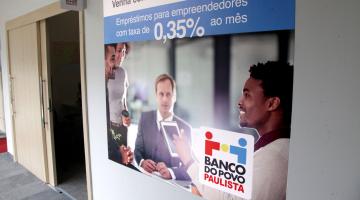 Painel do  Banco do Povo afixado em parede. #Pracegover