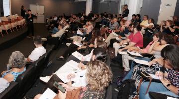 audiório com pessoas sentadas assistindo palestra. #paratodosverem