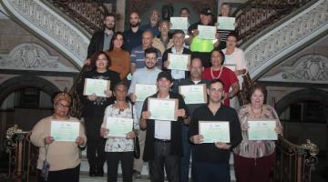 todos os homenageados posam para foto em escadaria do saguão da prefeitura. eles seguram seus respectivos certificados. #paratodosverem 