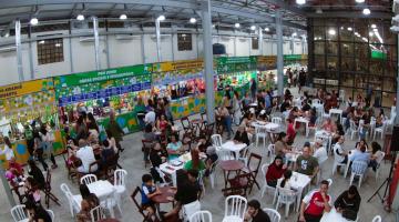 #paratodosverem galpão lotado com pessoas sentadas em cadeiras junto às mesas