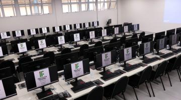 sala de aula com mesas e desktops. #paratodosverem