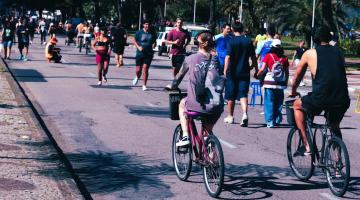 pessoas andam de bicicleta e caminham na avenida da praia. #paratodosverem 