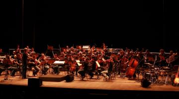 Orquestra se apresentando em um palco. #paratodosverem