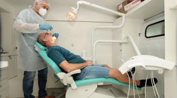 dentista atende homem que está na cadeira do consultório móvel. #paratodosverem