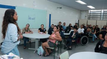 palestra em sala de aula com adultos e alunos sentados. #paratodosverem 