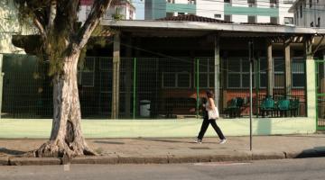 a fachada da unidade com uma árvore na frente uma pessoa andando na calçada. #paratodosverem