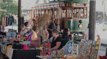 feira de artesanato com o bonde turístico ao fundo. #paratodosverem
