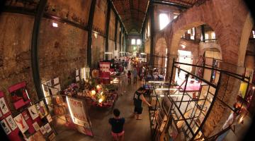 estandes de exposição montados em corredor de antigo prédio.#paratodosverem 