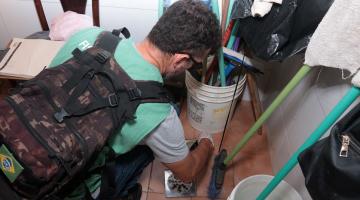 homem agachado fiscaliza ponto de uma casa #paratodosverem