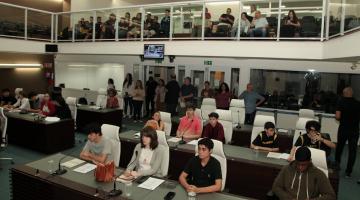 jovens estão sentados em tribuna da câmara municipal. #paratodosverem 