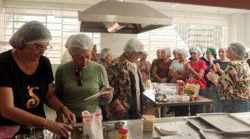mulheres em torno de fogão industrial em aula de culinária. #paratodosverem