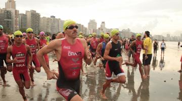 Atletas estão ingressando no mar para prova aquática. #pracegover