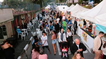 pessoas circulando perto de barracas de evento #paratodosverem