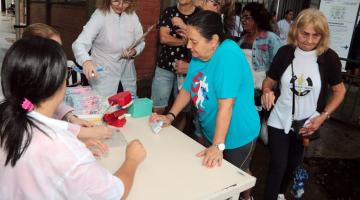 mulheres se juntam em torno de mesa ode há orientação sobre higiene bucal e entrega de kits. #paratodosverem 
