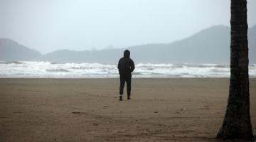 pessoa agasalhada sozinha na praia. #paratodosverem