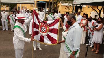 3 pessoas seguram estandarte de escola de samba #paratodosverem