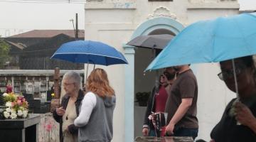 pessoas olhando túmulos em cemitério #paratodosverem