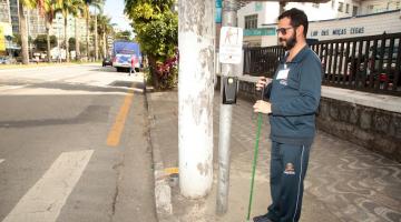 homem está ao lado de botoeira em poste pronto para fazer a travessia de pedestres. #paratodosverem