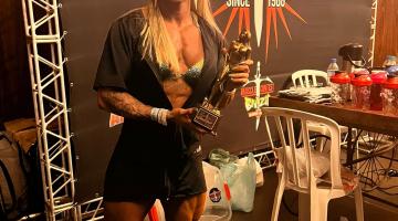 a fisiculturista posa para foto segurando troféu. #paratodosverem