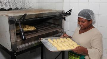 mulher olha pães retirados de forno #paratodosverem