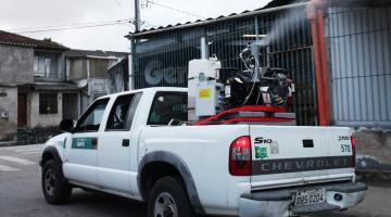 carro com equipamento de dispersão de líquido percorre rua. #paratodosverem