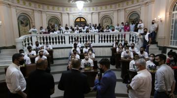 Autoridades discursam em pé para atletas sentados na galeria da Sala Princesa Isabel. #pracegover