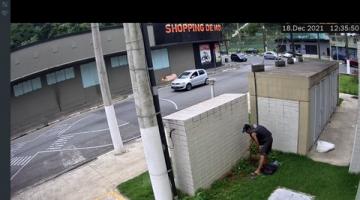 homem está puxando fio do solo junto a caixas de máquinas ao lado de posta.Imagem é de captação por câmera de monitoramento. #paratodosverem