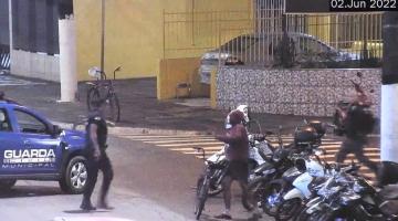 guarda municipal se aproxima de homem que está junto a bicicleta em rua. A viatura da guarda está ao lado #paratodosverem