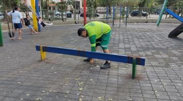 peça é removida de playground por homem. Ao fundo, uma criança brinca em balancê. #paratodosverem