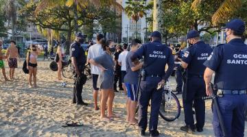 guardas municipais estão em torno de pessoas na faixa de areia. #paratodosverem