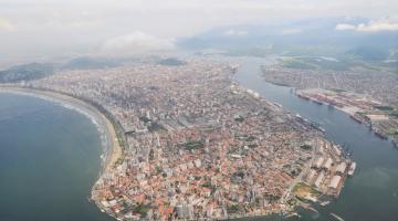 Vista panorâmica da cidade onde se vê a ilha contornada por mar, toda a extensão do porto e, do outro lado, da orla. #Paratodsoverem