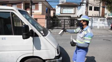 Agente da CET segura folheto diante de van para prender no para-brisa