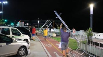 homens carregam gradis para serem instalados no acesso ao calçadão, na ponta da Praia. Alguns já estão instalados. É noite e os postes estão acesos. #Paratodosverem