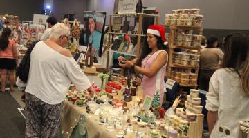 pessoas vendo produtos em feira #paratodosverem
