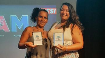 Glaucia e Deise posam para foto com troféus nas mãos. #paratodosverem