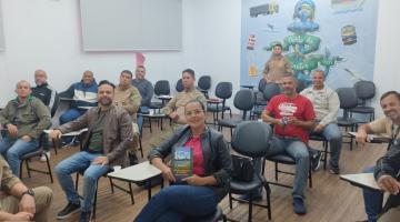 guardas portuários estão sentados em cadeiras de sala de aula. eles sorriem para a foto. #paratodosverem 