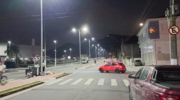 vista geral de avenida com luminárias de postes acesas à noite. #paratodosverem