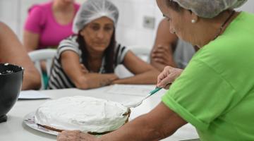 aluna está atenta à professora decorando bolo. #paratodosverem