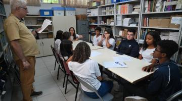 alunos conversam sentados em torno de mesa. #paratodosverem 