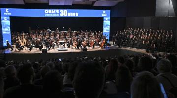 plateia e palco com músicos e coralistas. #paratodosverem
