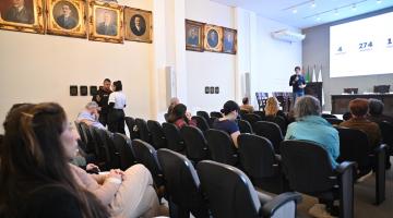auditório com pessoas sentadas assistindo palestra. #paratodosverem