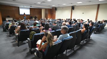 profissionais assistem palestra em auditório. #paratodosverem