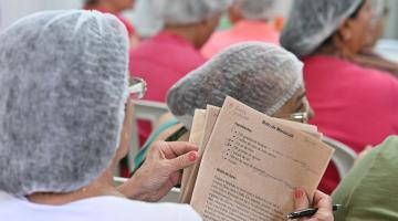 mulher está de costas segurando papel com receita de bolo. #paratodosverem