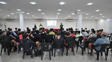 plateia sentada e duas pessoas em frente ao fundo #paratodosverem