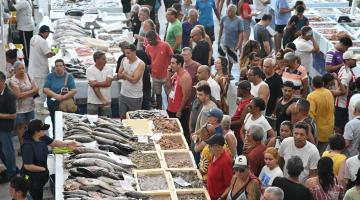inúmeros clientes diante de boxes de pescados. #paratodosverem 