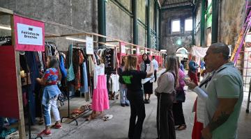 pessoas olhando roupas penduradas #paratodosverem