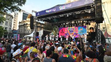 público lota praça. Palco com show ao fundo. #paratodosverem